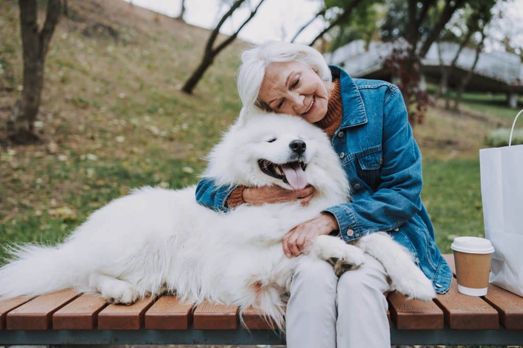A person hugging a large fluffy white dog representing the pet friendly lifestyle of the Ames Summerville apartments - Gallery Lifestyle 06