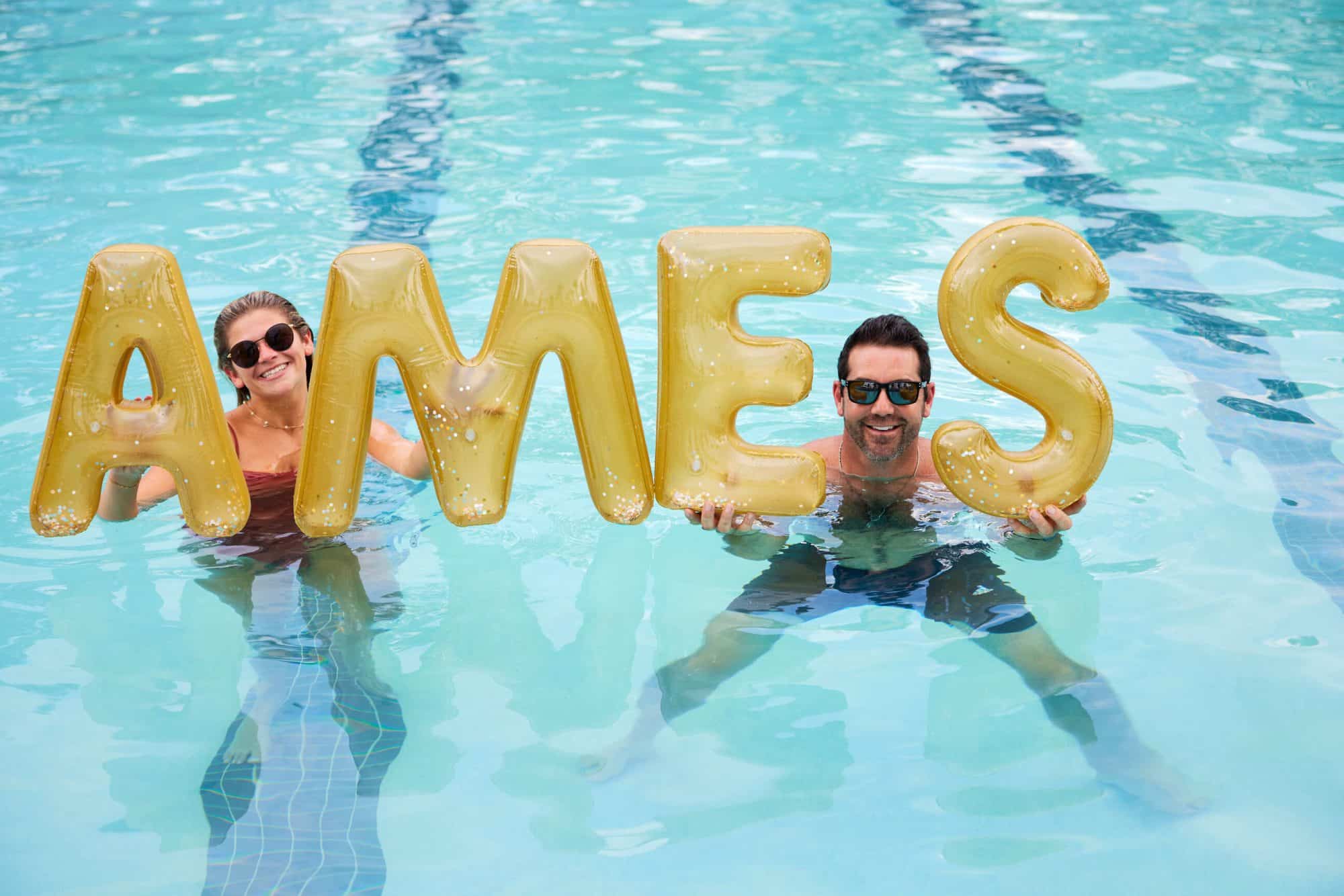 Two residents holding up baloons that spell out "Ames" in the pool