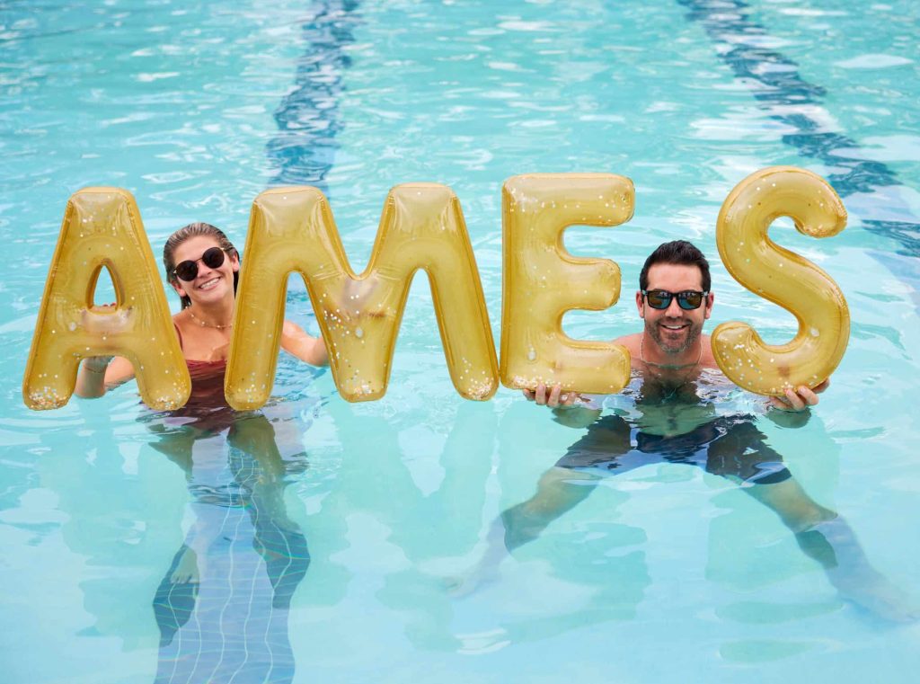 Two residents holding up baloons that spell out "Ames" in the pool