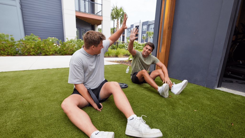 Two male residents working out in the outdoor space in The Ames' community fitness center