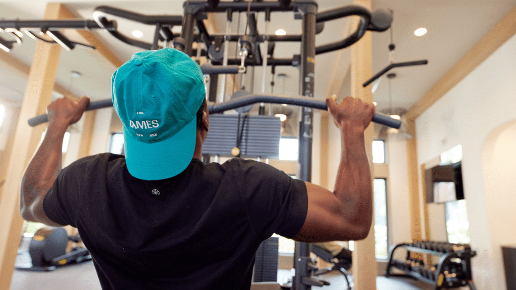 Resident at The Ames working out in the community fitness center with a community branded hat