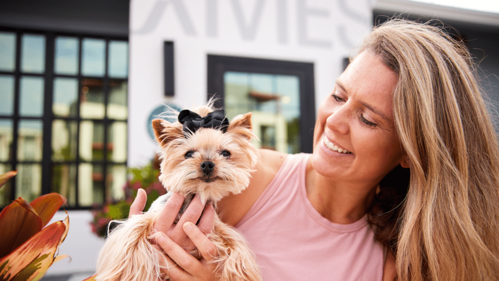 A resident with her dog in front of The Ames clubhouse