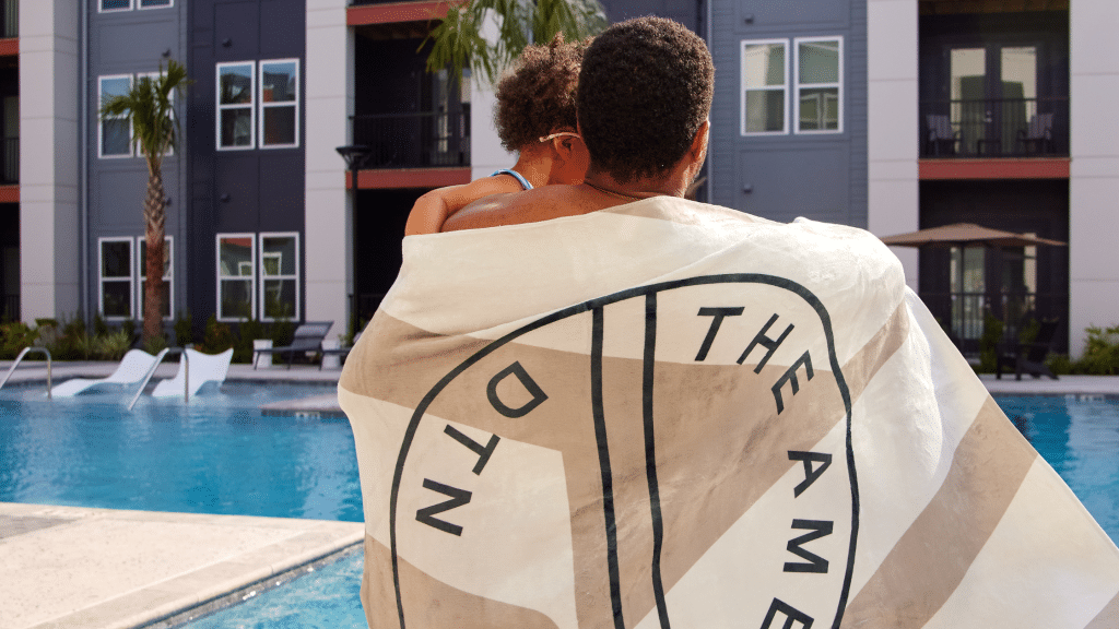 A resident by the pool wrapped in a 'The Ames' branded towel